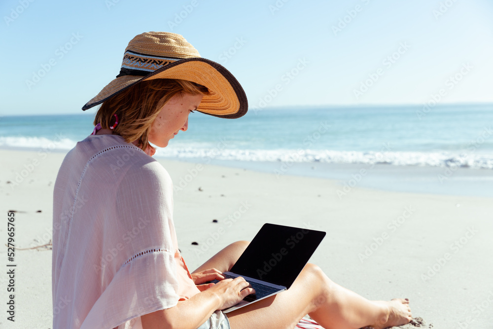 Caucasian woman using her laptop seaside