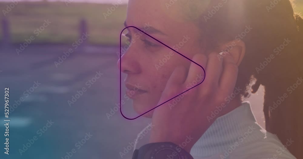 Neon purple play icon against close up of african american woman wearing earphones Neon purple play icon against close up of african american woman wearing earphones