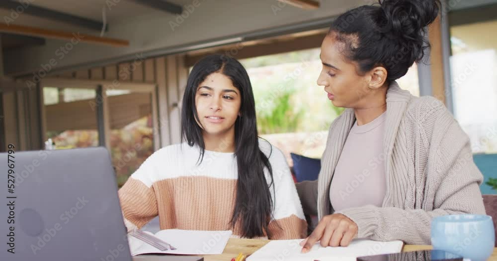 Video of focused biracial women working from home with laptop