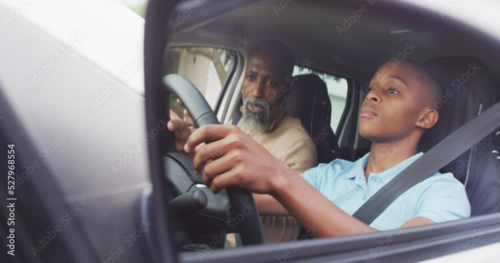 Video of focused african american father learning son how to drive a car