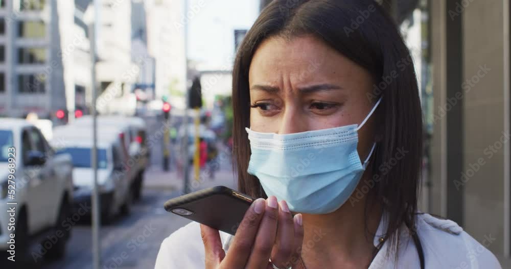 African american woman wearing face mask talking on smartphone in street African american woman wearing face mask talking on smartphone in street