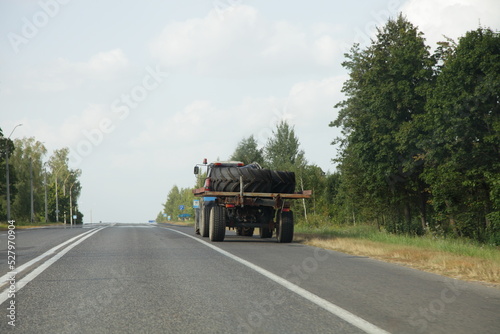 Tractor trailer with big tires on country road at summer day