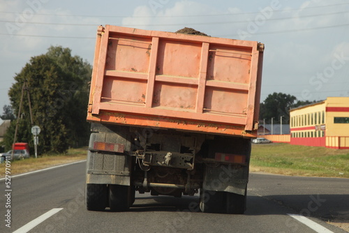 Obraz na płótnie Heavy overloaded dump truck with lurch carries sand on a European countryside asphalt road at summer day w salonie