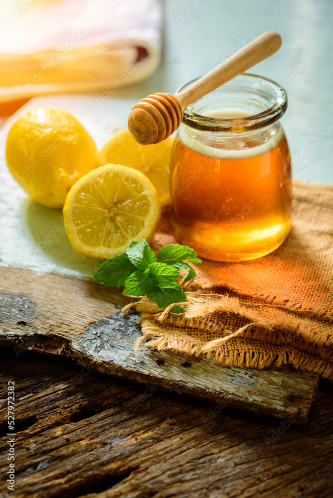 Honey with fresh lemon on wooden table background, honey dipper Honey with fresh lemon on wooden table background, honey dipper