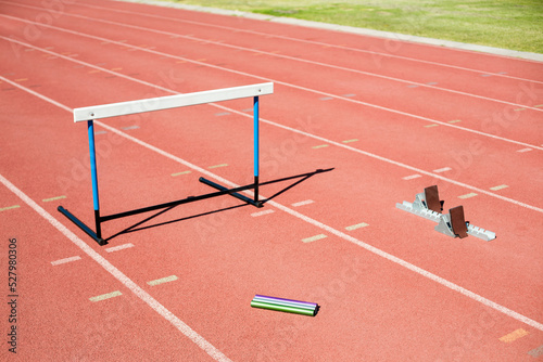 High angle view of baton with track starting block and hurdle on field