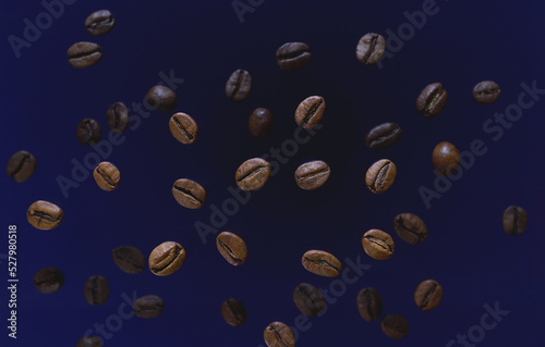 Coffee beans top view blue background. Coffee beans spill. Scattered coffee grains. Flying coffee beans. Caffeine, aroma, fresh taste. Morning refreshing drink ingredient