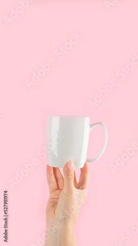 Arms raised up holding coffee cup on pink background.