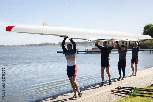 Senior caucasian rowing team carrying boat together to the lake photo