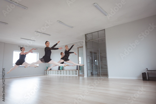 Caucasian female attractive ballet dancers in black suits practicing during a ballet class photo