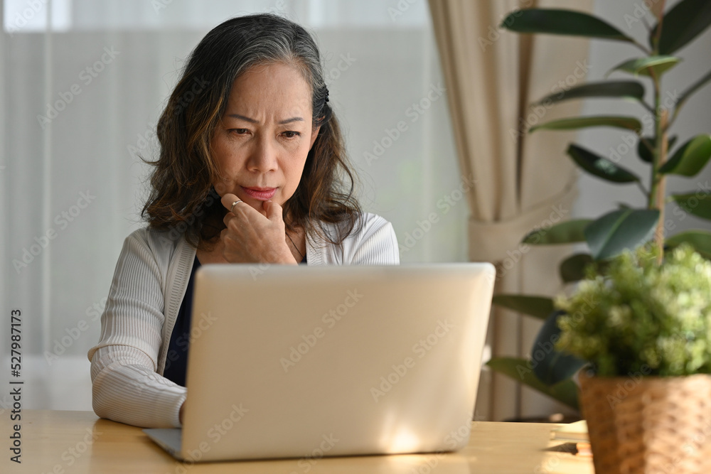 Thoughtful confused 60s middle aged business lady concerned thinking about online working, remote working from home. Thoughtful confused 60s middle aged business lady concerned thinking about online working, remote working from home.