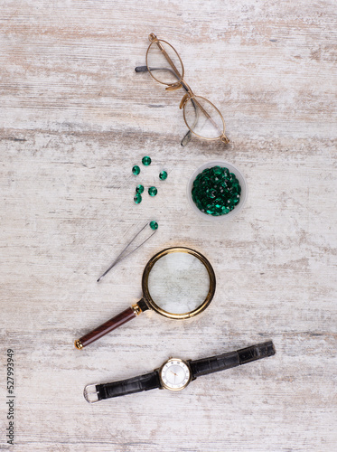 magnifying glass and emeralds on the table