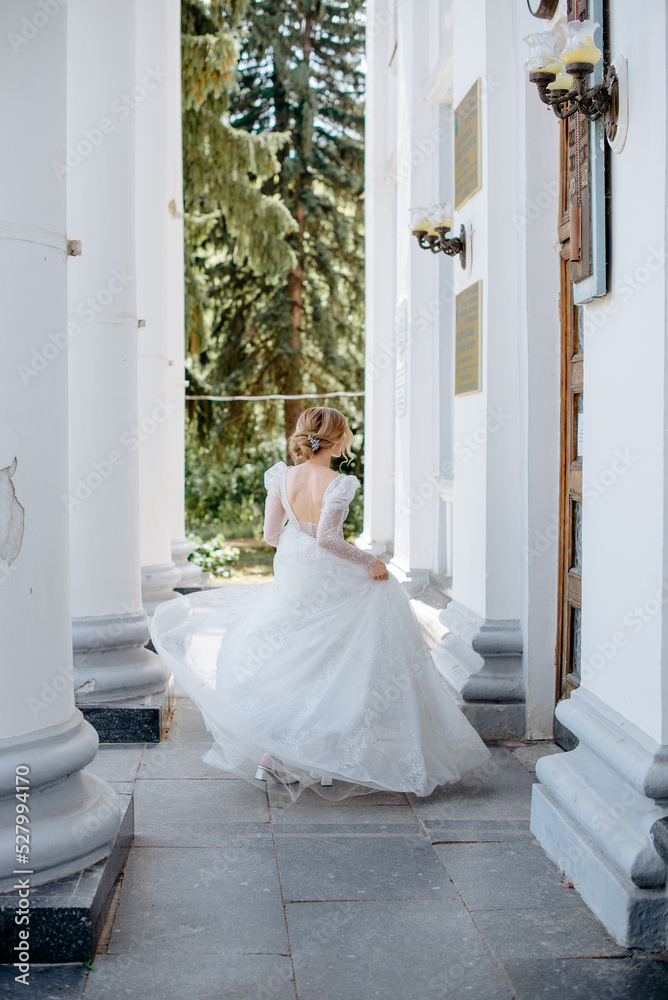 Fototapeta premium a young bride in a wedding dress dances standing with her back