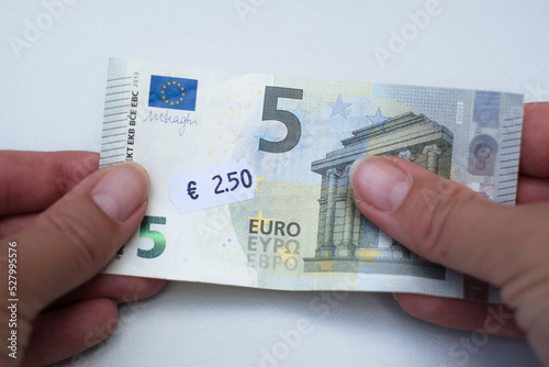 Five euro banknote with 2 euro 5 cent price tag. Selective focus on label. Inflation in Europe, hyper inflation, devaluation of fiat money concept. photo