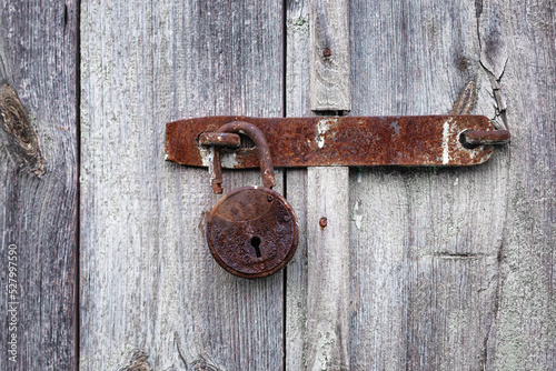 Rusty padlock on the old wooden door of the house, barn. Old hanging metal door lock on a wooden background. photo