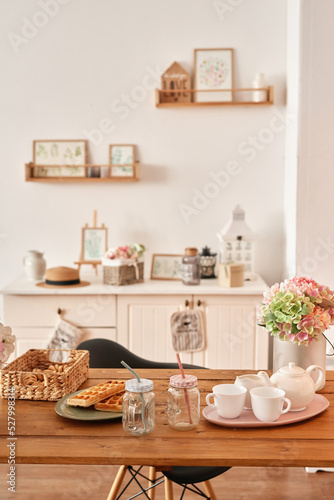 White kitchen interior in loft style. Shelves with pink crockery and kitchen utensils. Studio apartment. Rent and delivery of housing. Hostel and hotel © Aleksandr