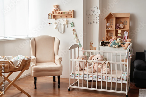 Scandinavian style white interior children's room, bedroom, nursery. Baby cot with canopy. Wooden shelves and toys.