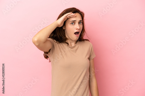 Young caucasian woman isolated on pink background doing surprise gesture while looking front © luismolinero