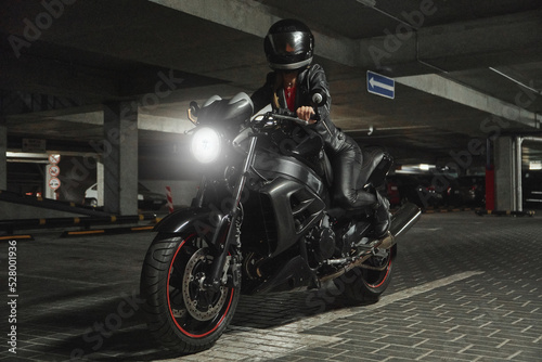 Young woman biker in a helmet sitting on a motorcycle in the underground parking garage