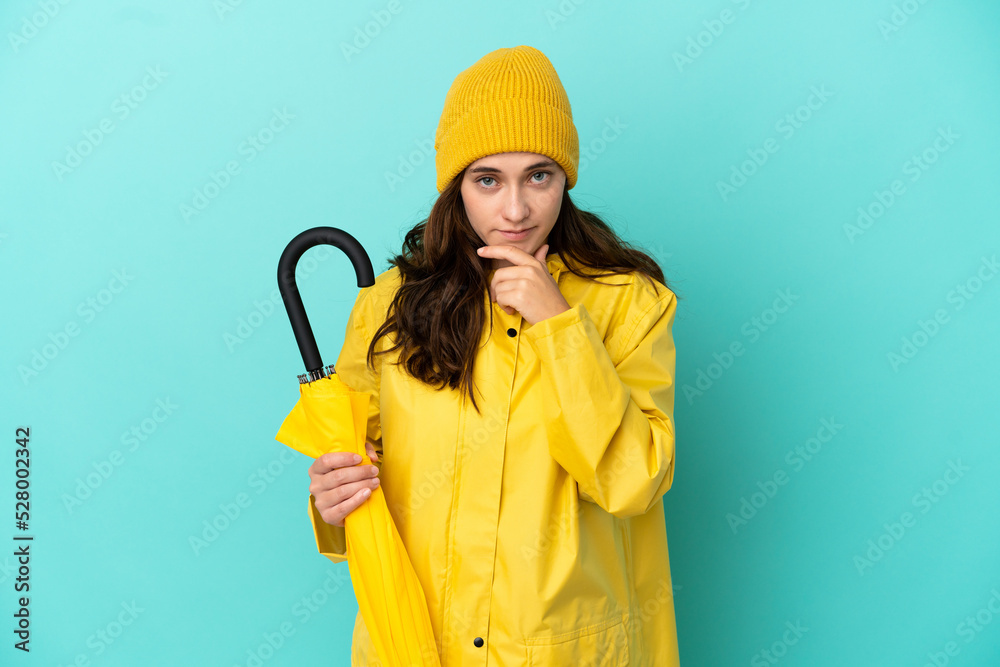 Young caucasian man holding an umbrella isolated on blue background thinking Young caucasian man holding an umbrella isolated on blue background thinking