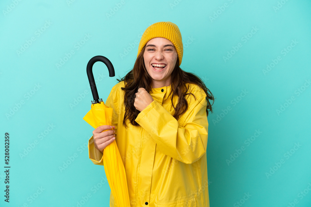 Young caucasian man holding an umbrella isolated on blue background celebrating a victory Young caucasian man holding an umbrella isolated on blue background celebrating a victory