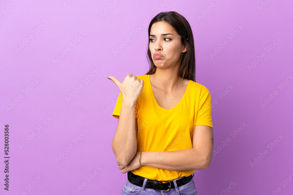 Young caucasian woman over isolated background unhappy and pointing to the side Young caucasian woman over isolated background unhappy and pointing to the side