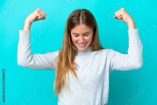 Young blonde woman isolated on blue background doing strong gesture