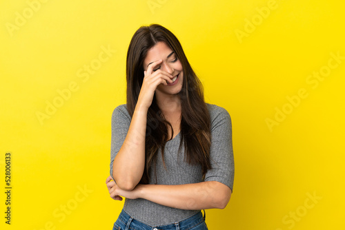 Young Brazilian woman isolated on yellow background laughing © luismolinero