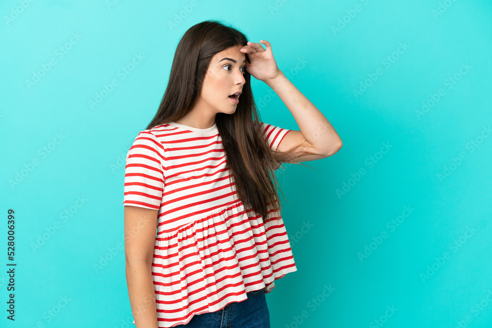 Young Brazilian woman isolated on blue background with surprise expression while looking side Young Brazilian woman isolated on blue background with surprise expression while looking side