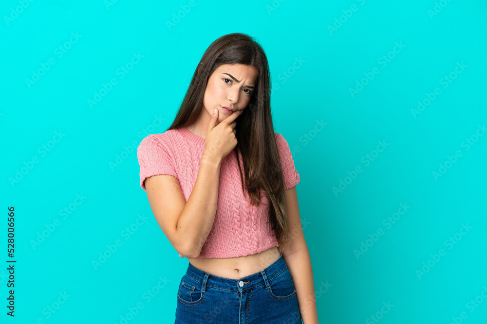Young Brazilian woman isolated on blue background having doubts Young Brazilian woman isolated on blue background having doubts