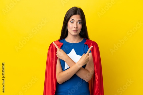 Super Hero Brazilian woman isolated on yellow background pointing to the laterals having doubts © luismolinero