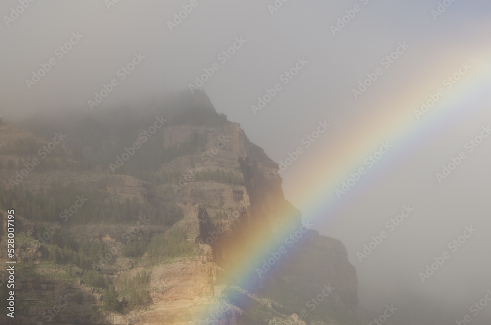 Rainbow and Tirajana cliffs in the fog. Cliffs of Tirajana Natural Monument. San Bartolome de Tirajana. Gran Canaria. Canary Islands. Spain.
