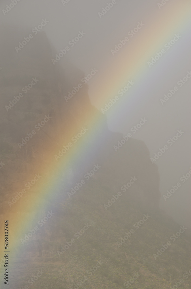 Rainbow and Tirajana cliffs in the fog. Cliffs of Tirajana Natural Monument. San Bartolome de Tirajana. Gran Canaria. Canary Islands. Spain. Rainbow and Tirajana cliffs in the fog. Cliffs of Tirajana Natural Monument. San Bartolome de Tirajana. Gran Canaria. Canary Islands. Spain.