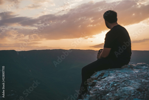 silhouette of person sitting on rock