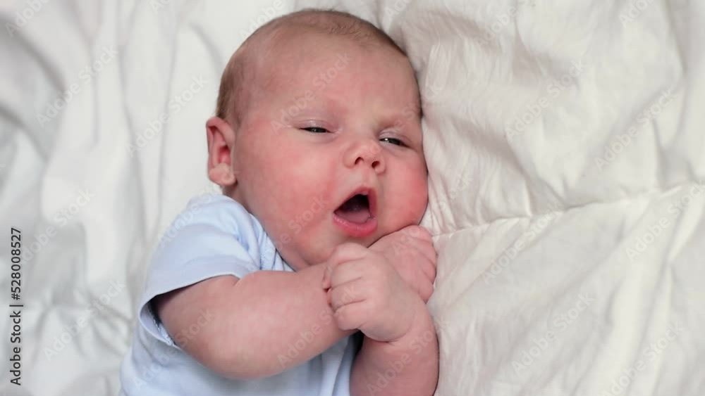 Closeup portrait of Newborn baby on white blanket. Soft focus. Infant is lying, yawning. One, two week age. Infant girl waking up on bed at home. New life and growing up concept. Real People. Closeup portrait of Newborn baby on white blanket. Soft focus. Infant is lying, yawning. One, two week age. Infant girl waking up on bed at home. New life and growing up concept. Real People.