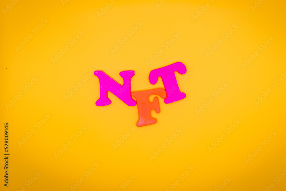 Non fungible token. NFT acronym of multicolored letters on yellow background. Crypto Art concept. Copy space Non fungible token. NFT acronym of multicolored letters on yellow background. Crypto Art concept. Copy space
