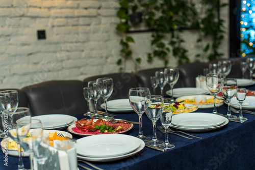 beautifully laid tables with glasses, appliances and appetizer in restaurant