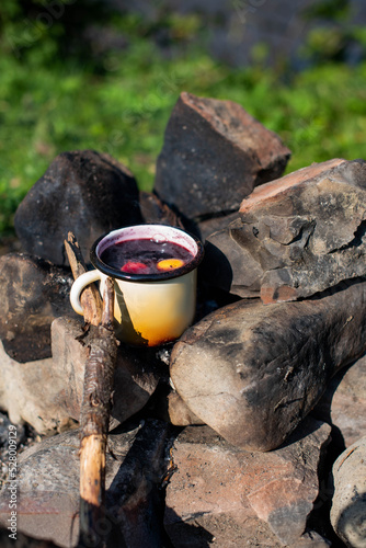 Small camp fire with hot mulled wine in an iron mug