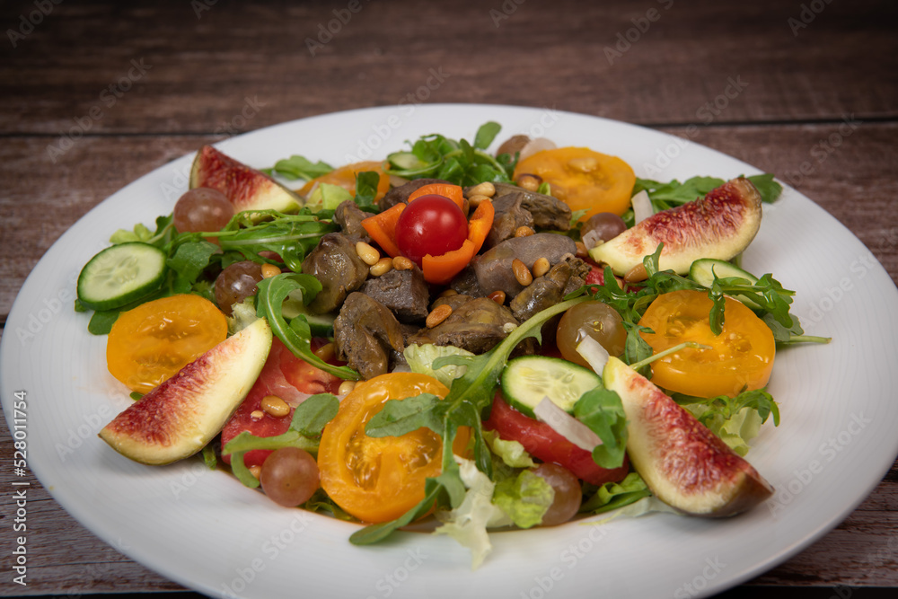 Recipe for fried chicken liver and gizzards with salad and tomatoes, cucumber, figs, grapes on a white plate, High quality photo Recipe for fried chicken liver and gizzards with salad and tomatoes, cucumber, figs, grapes on a white plate, High quality photo