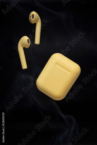 Yellow Earphones with Wireless Charging Case on Black Background with Smoke.