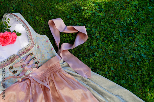 	 a beautiful traditional Bavarian dirnd or also Austrian dirndl dress (usually worn at Oktoberfest in Munich) lying on the green meadow	