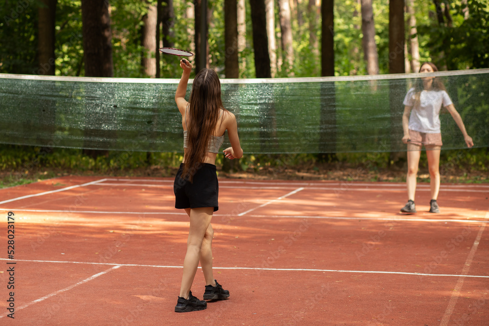 badminton player on badminton court, two girls play in the park in nature, sports and recreation