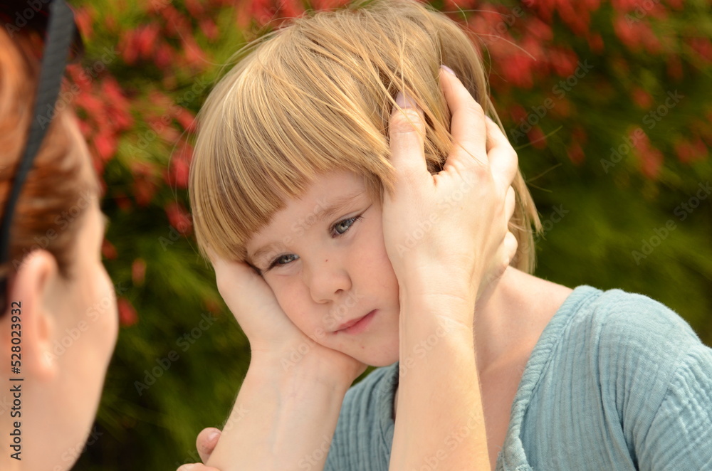 Portrait of a little boy, close-up. face of a child in mother's hands. Women's hands painfully stroking her son's face. Concept: maternal care, maternal love, tenderness, affection, maternal instinct,