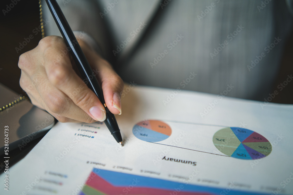Close-up a business hand signing documents for approval, agreement with partners, working on laptop computer on desk in modern office Close-up a business hand signing documents for approval, agreement with partners, working on laptop computer on desk in modern office