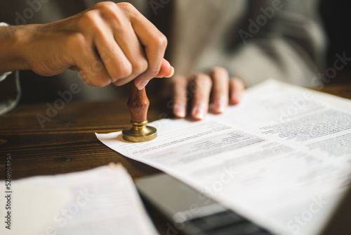 Fotografia, Obraz close-up of person stamping documents to approve agreements,
