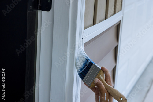 Fototapeta Naklejka Na Ścianę i Meble -  Paintbrush are used by a contractor painter to paint wooden moldings on door trims
