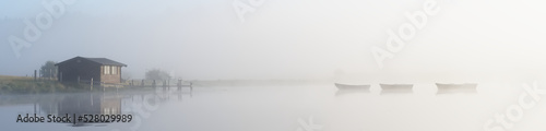 Fishing boats in lake and early morning mist at sunrise