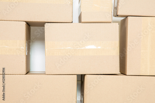Foto Stack of cardboard boxes for moving, Empty room with a white wall and cardboard boxes with unbranded barcode on the floor