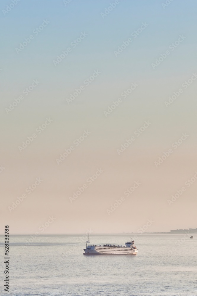 Transport boat sailing through the sea during sunset, off the coast of Malaga moving away from the city Transport boat sailing through the sea during sunset, off the coast of Malaga moving away from the city