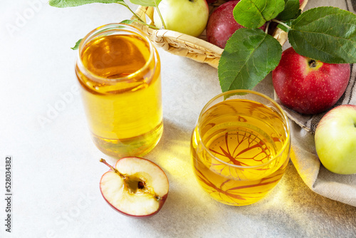 Apple juice in a glass and fresh apples on a stone tabetop. Autumn vitamin drink juice apple. Copy space. photo