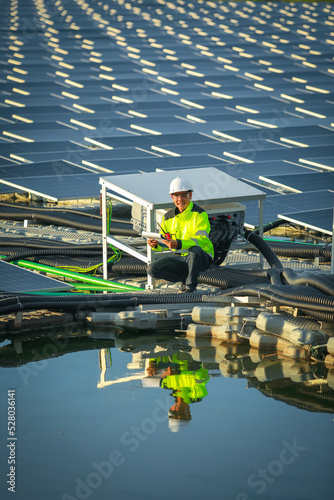 Portrait of professional man engineer working checking the panels at solar energy on buoy floating. Power plant with water, renewable energy source. Eco technology for electric power in industry.